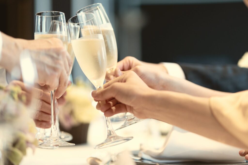 レセプションのテーブルで、シャンパングラスを合わせて乾杯するゲストたち