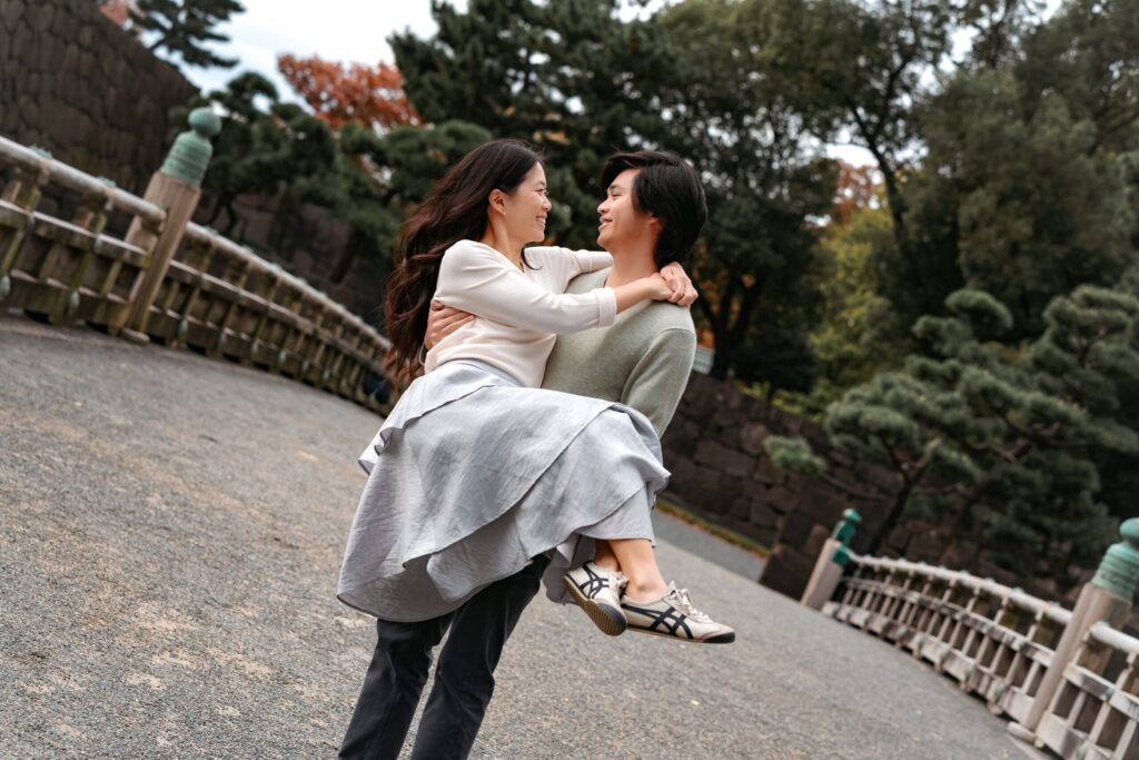 皇居近くの橋の上で、パートナーを抱き上げて笑い合うふたり