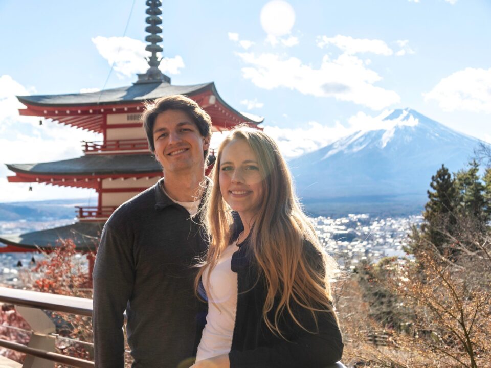 新倉山浅間公園の忠霊塔と雪をかぶった富士山を背に、笑顔で並ぶカップル